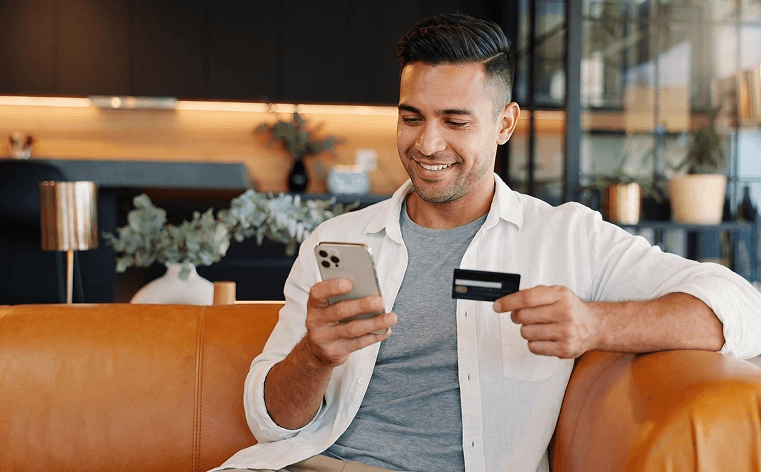 A customer paying with a card while messaging on a phone