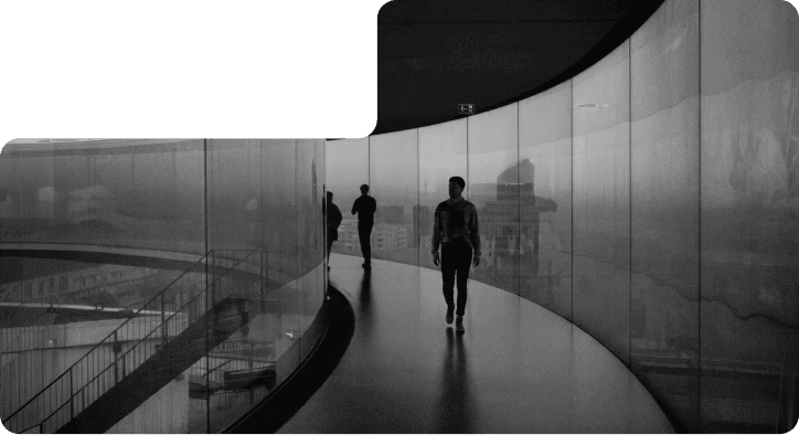 A person walking along a curved glass-walled skywalk