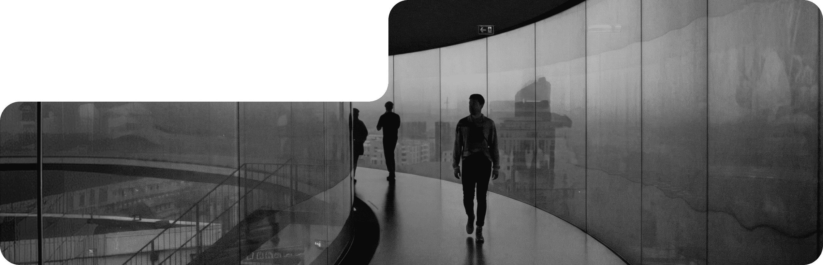 A person walking along a curved glass-walled skywalk